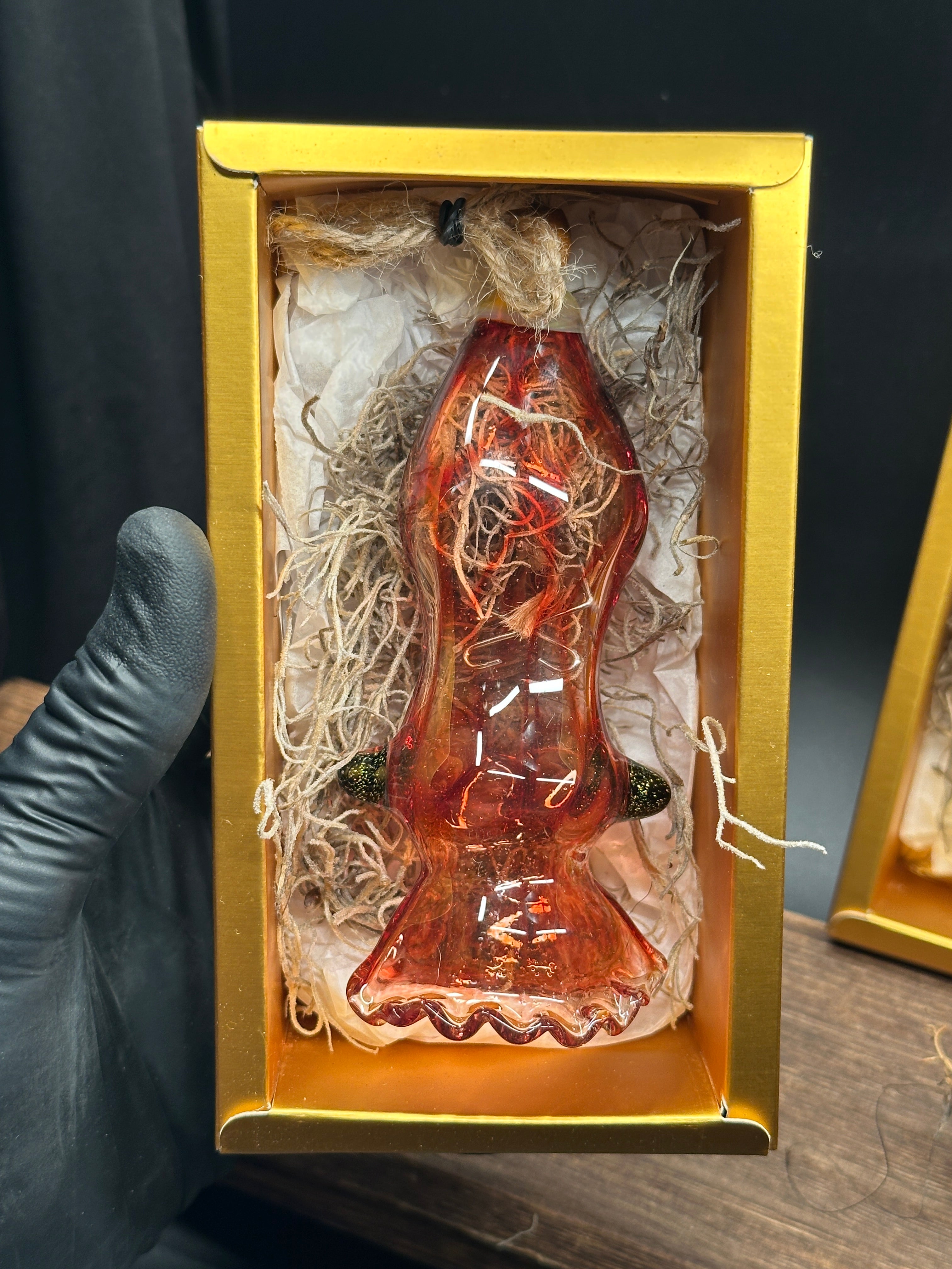 A flameworked and hand-spun blown glass squid air plant holder featuring detailed glass fins, custom eyes, and an integrated patented clip holding a live air plant.