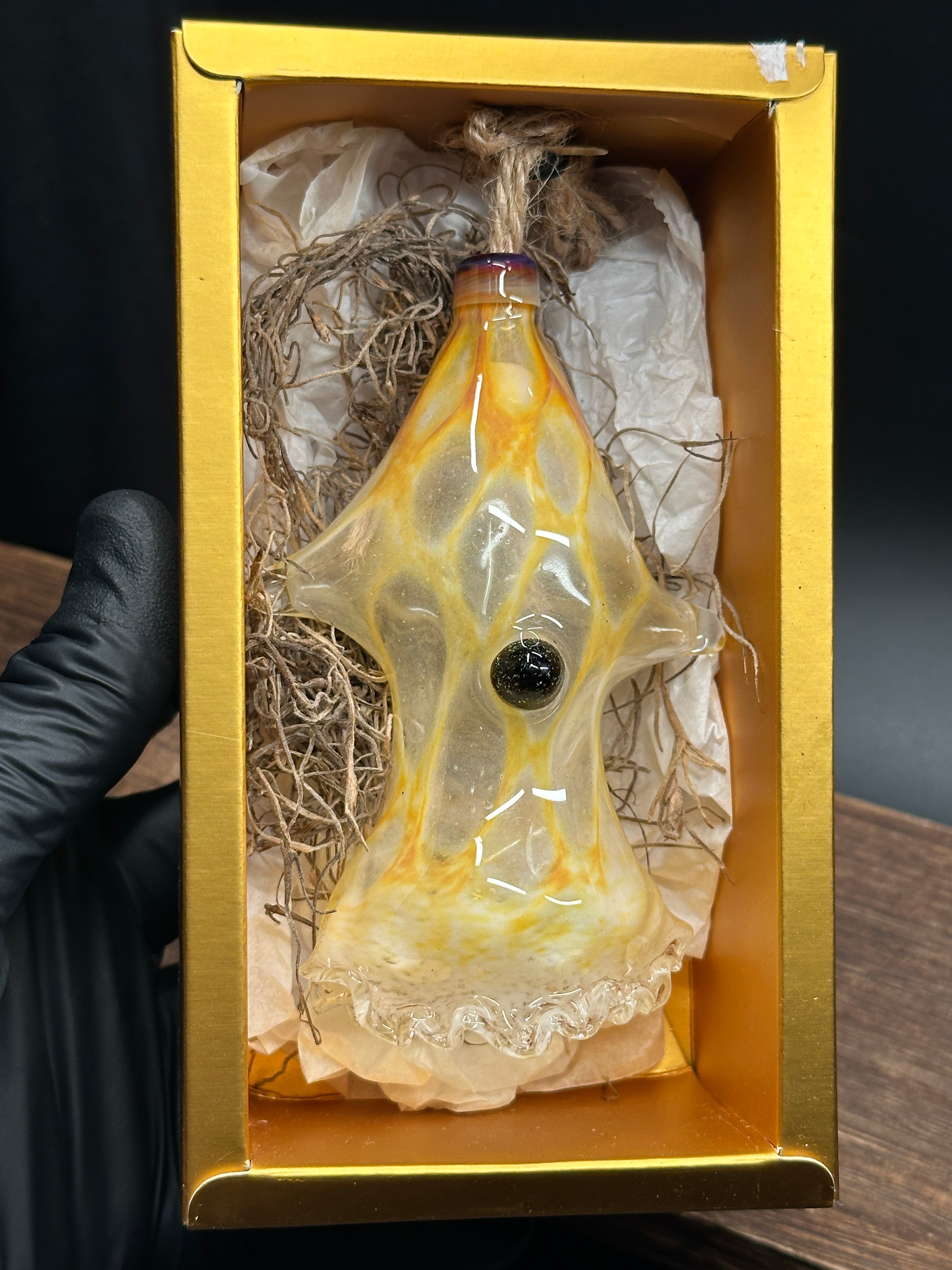 A flameworked and hand-spun blown glass squid air plant holder featuring detailed glass fins, custom eyes, and an integrated patented clip holding a live air plant.