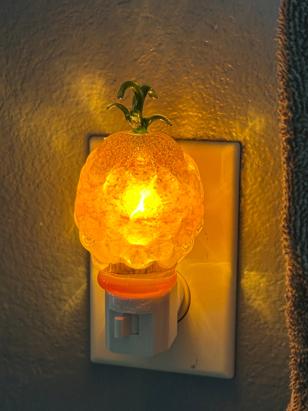 A flameworked and hand-spun blown glass pineapple night light featuring a detailed green crown and a textured yellow frit body that diffuses a warm, amber glow.